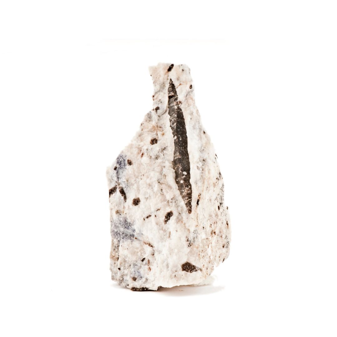 Corundum, a white mineral with dark specs on a white background.